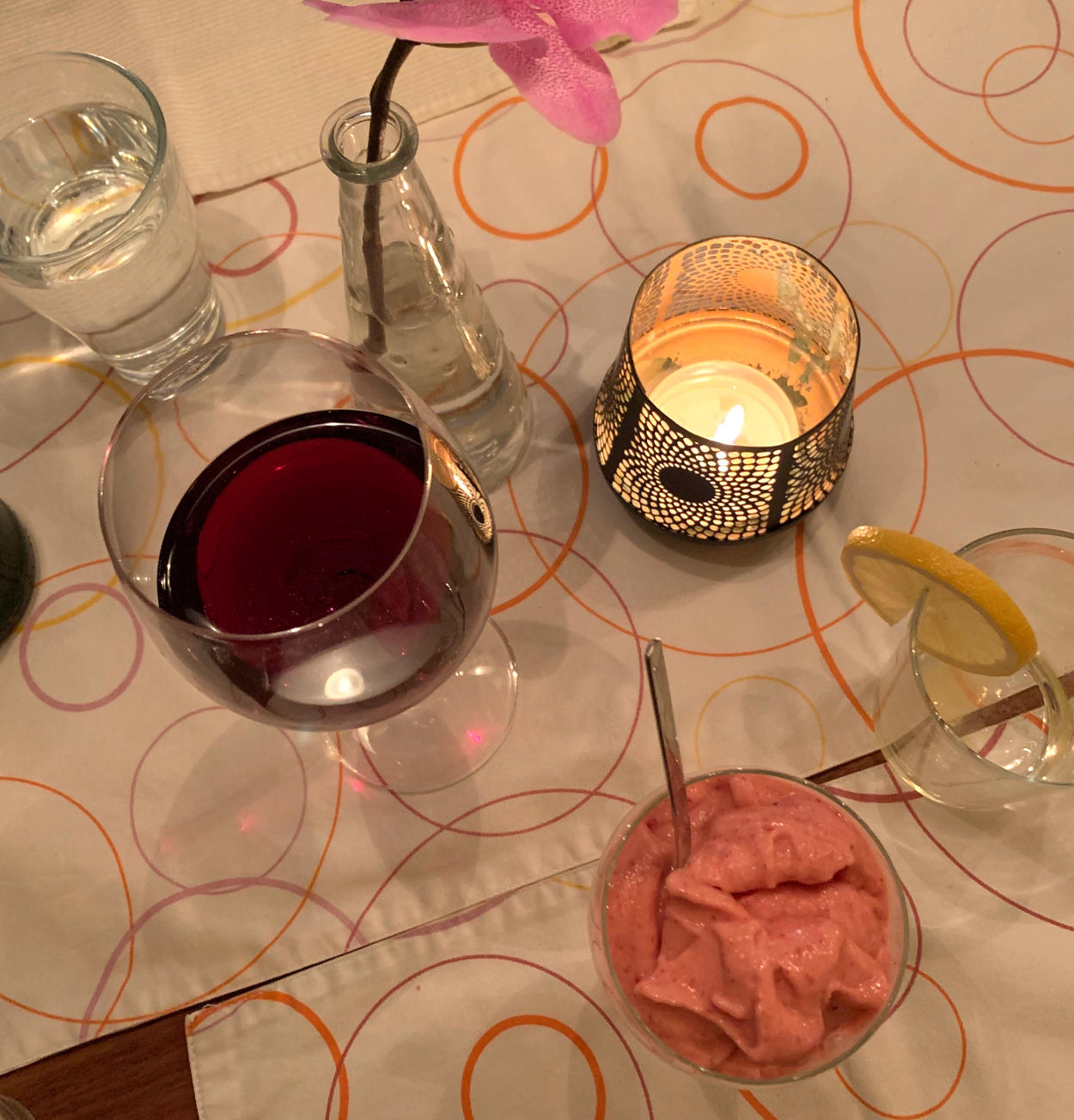 Ein Glas Rotwein, ein leeres Glas mit Zitronenscheibe, ein Glas Wasser, ein Glas mit Erdbeereis. 