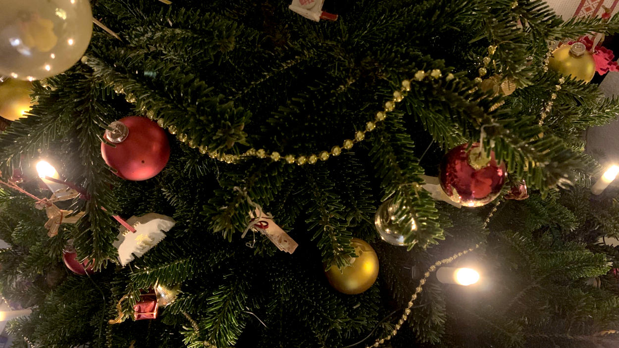 Teile des Baums aus der Vogelperspektive mit Kugeln, einer goldenen Kette und künstlichen Kerzen