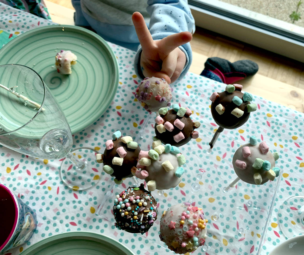 Cakepops, verziert mit Marshamllows, und eine Kinderhand