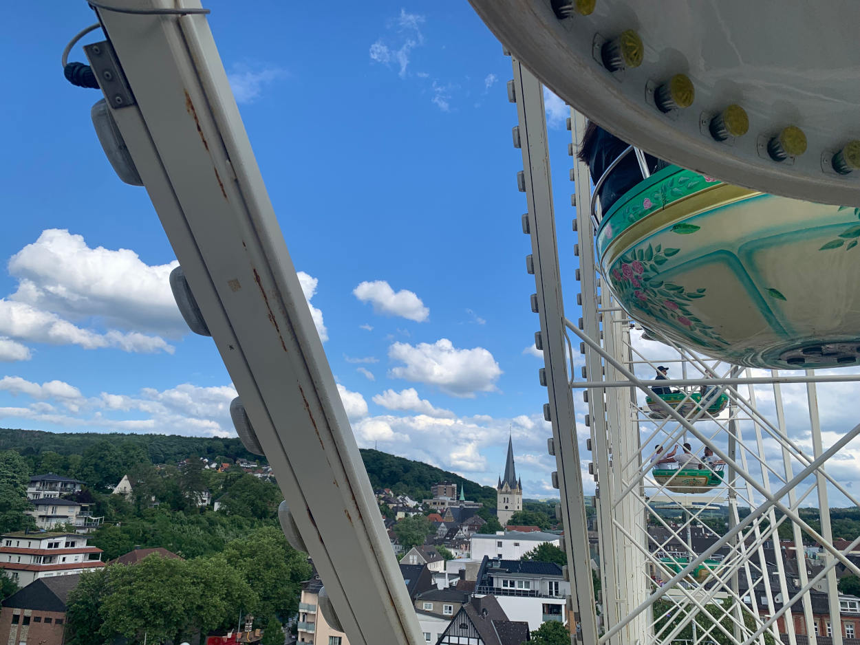 Blick aus der Gondel des RIesenrads aus sauerländische Kleinstadt mit Kirchturm, blauer Himmel Hügelketten
