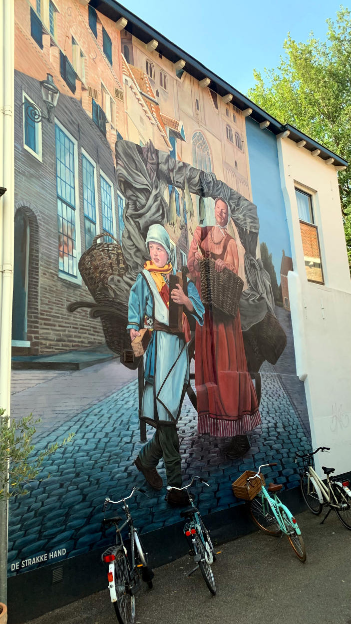 Bild an einer Hauswand: Frau ind Kinder im mittelalterlicher Kleidung mit Körben