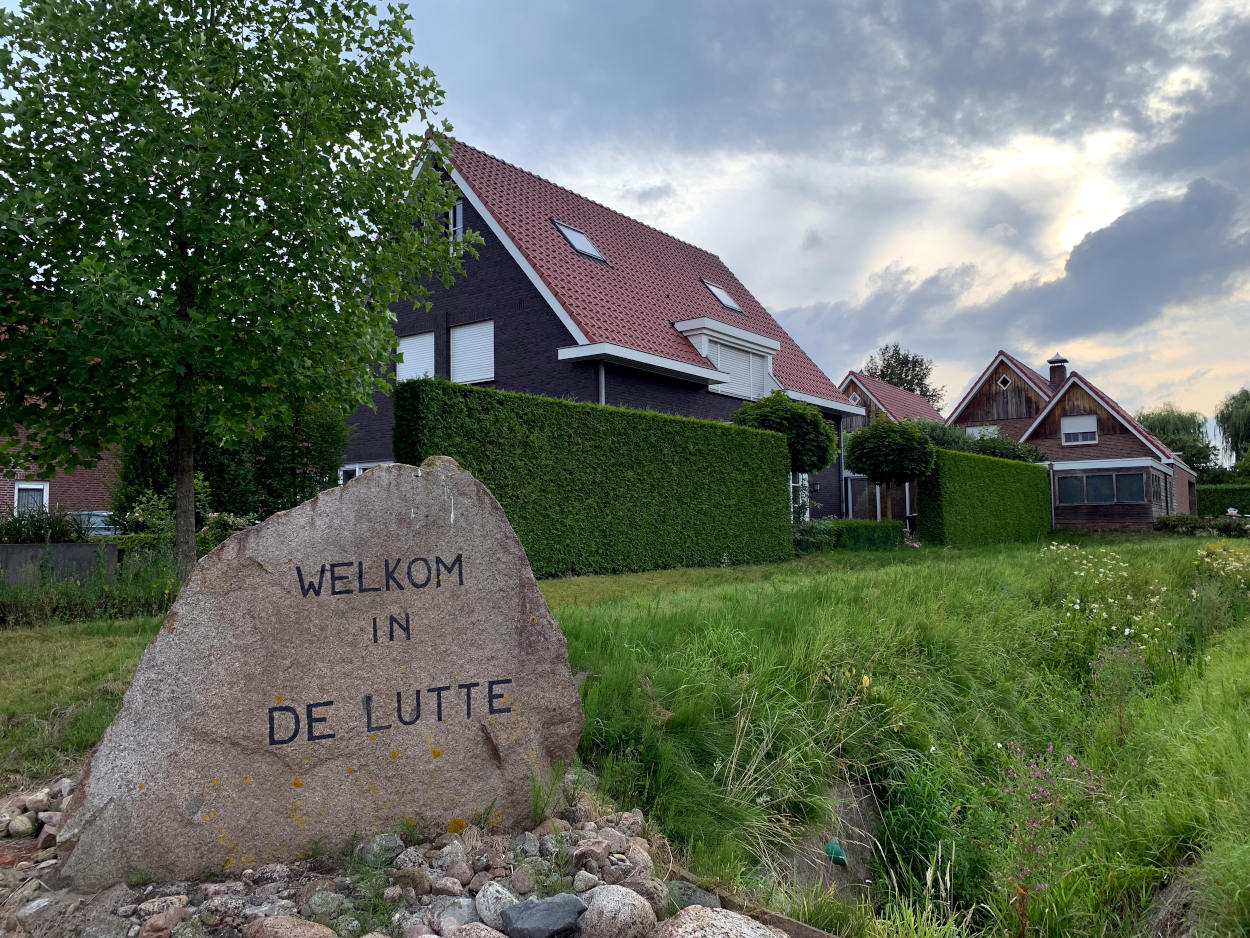 Stein mit Winschrift: Welkom in De Lutte, dahinter Wohnhäuser