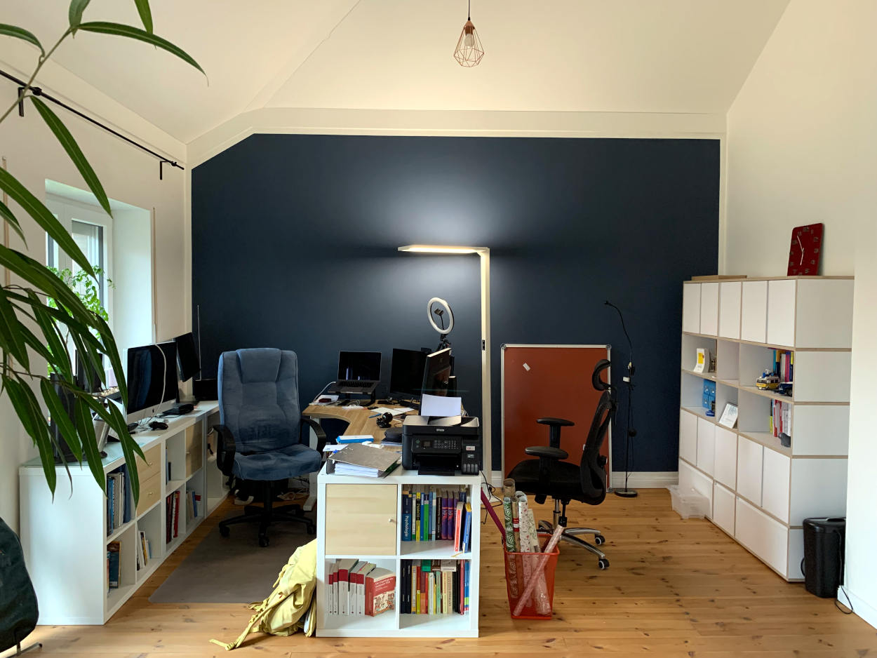 Homeoffice: Schreibtisch vor blauer Wand mit Regalen