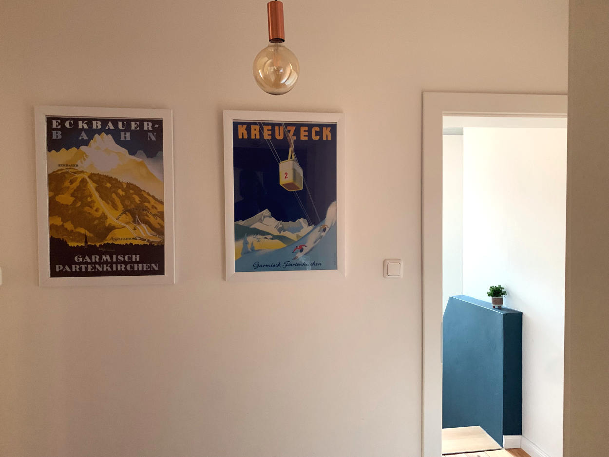 Zwei gerahmte Retro-Poster aus Garmisch-Partenkichen: ein Motiv mit gelb eingefärbten Bergen, Überschrift "Eckbauerbahn", und eine Gondel mit der Überschrift "Kreuzeck"