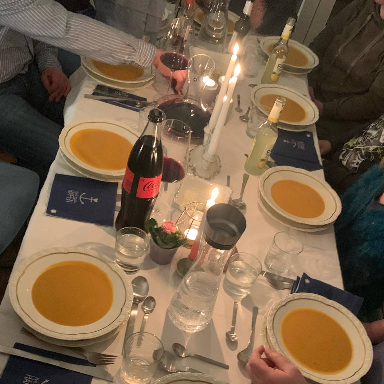 EIne gedeckte Tafel mit acht Tellern Suppe, Kerzen und Wien. 