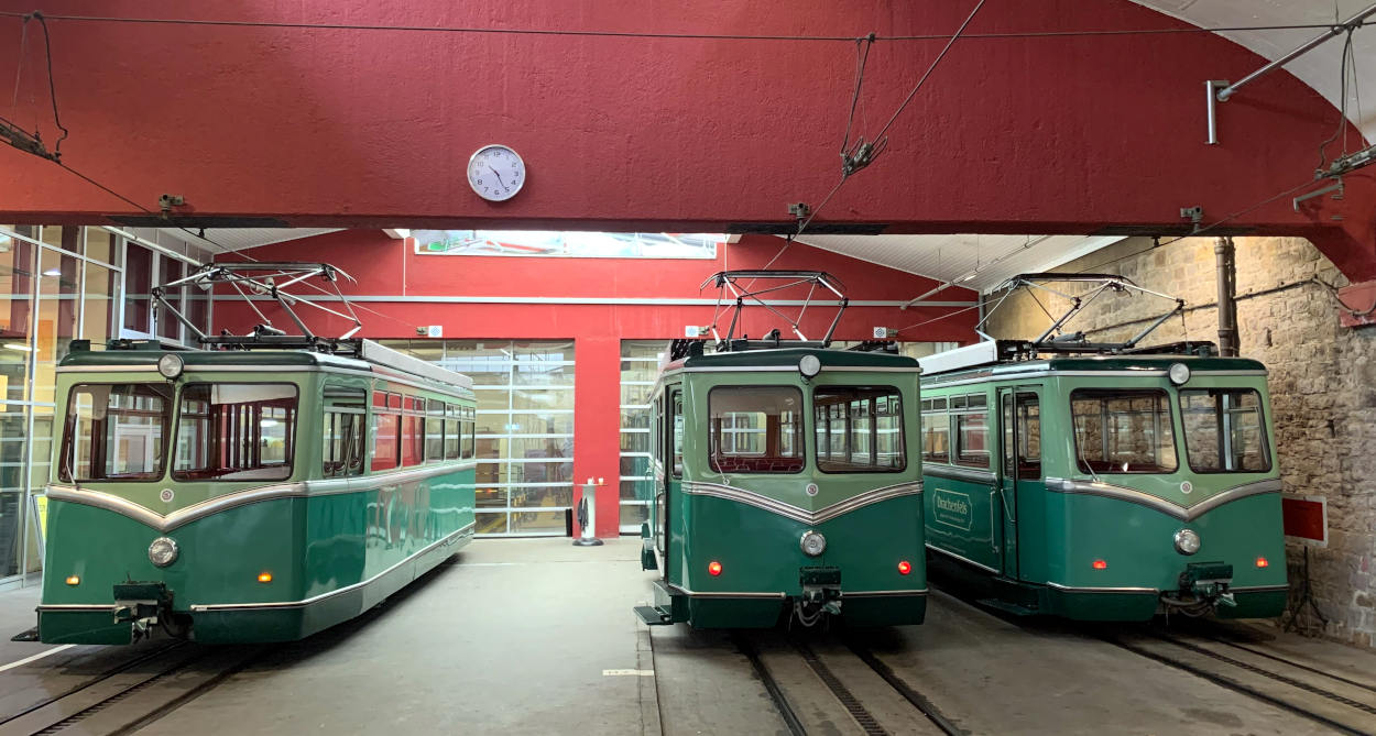 Zahnradbad auf den Frachenfels: Grüne, alte Bahnwaggons in einem roten Depot
