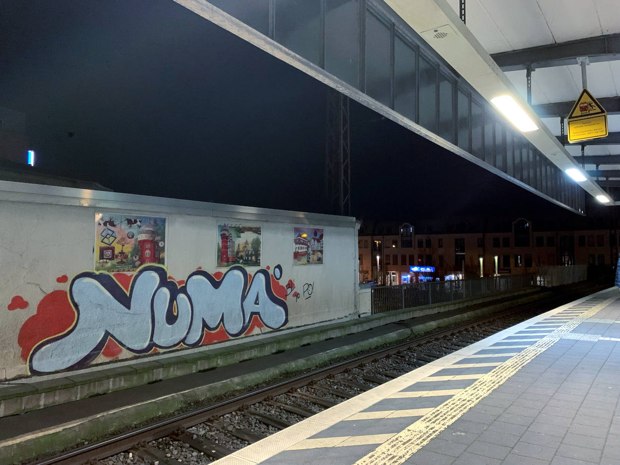 Gleis mit Graffit-Wand in Mülheim, erleuchtet von Scheinwerfern