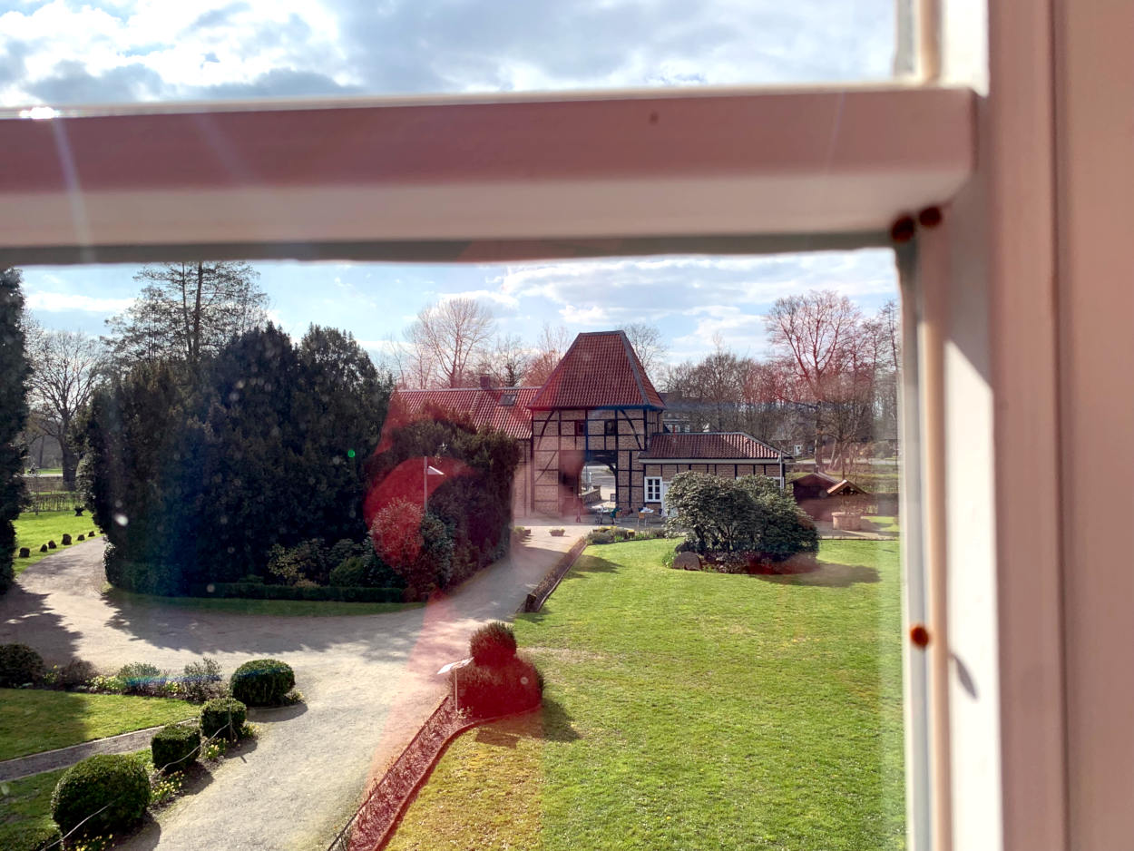 Blick durch das Fenster auf einen Fachwek-Torbogen, im Vordergrund unscharf ein Marienkäfer