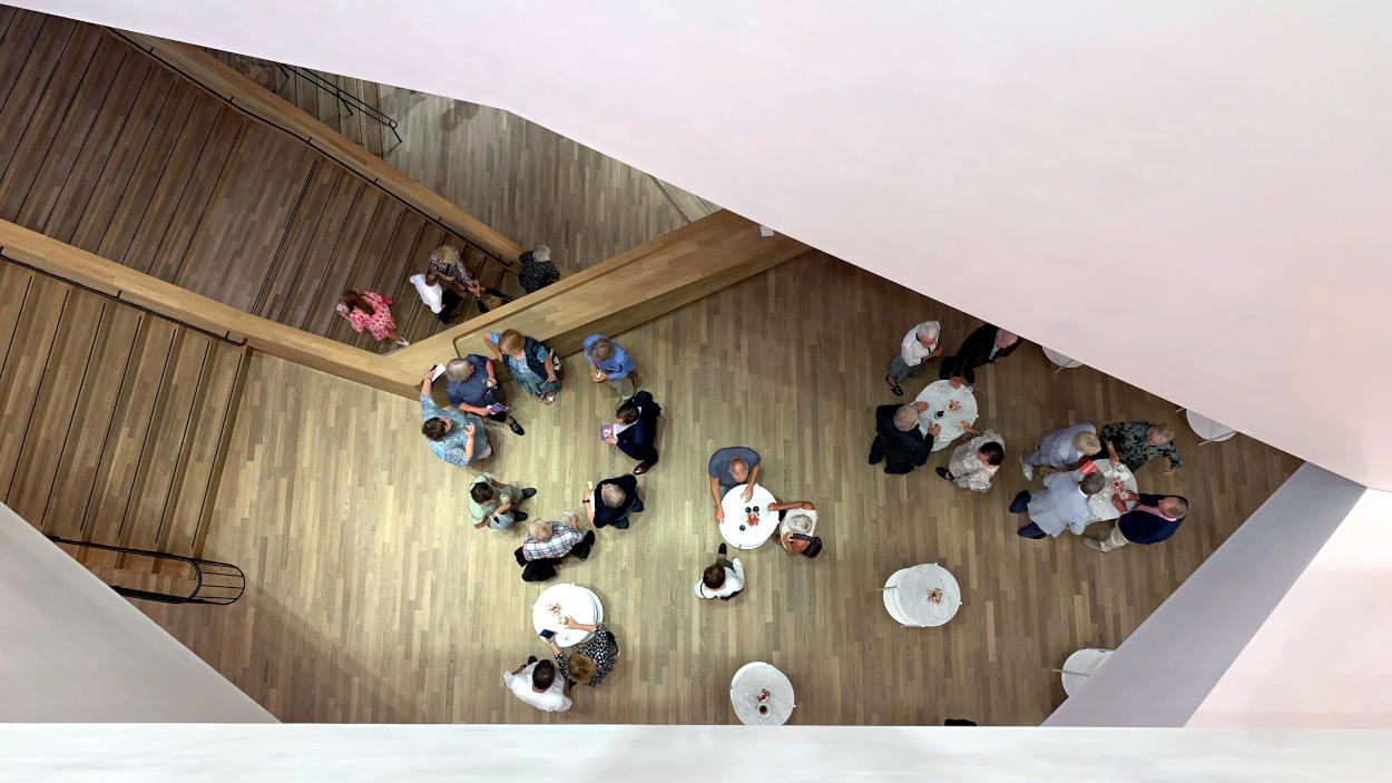 Blick hinunter in die Foyers der Elbphilharmonie. Menschen stehen an Tischen (Vogelperspektive).