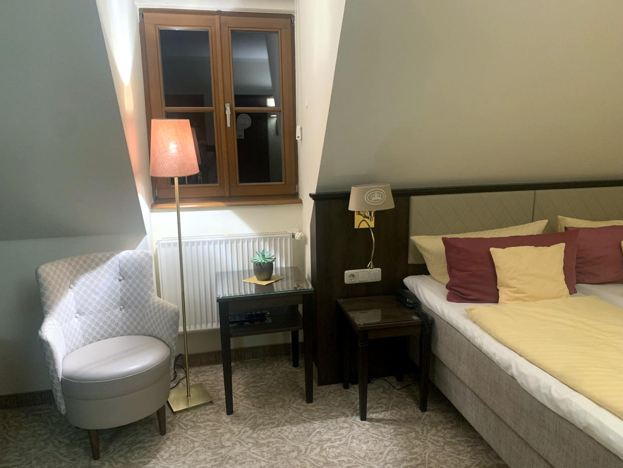 Hotelzimmer mit Doppelbett und Plüschsessel