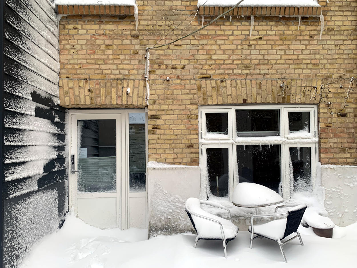 Haustür, davor ein Schneeberg - fotografiert von außen